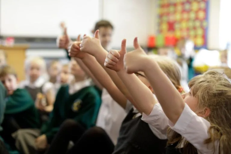 Photo of school children with their hands up