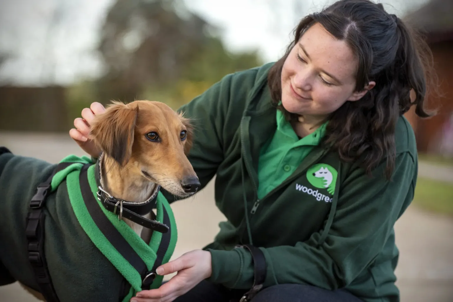 Smiling Woodgreen team member with a dog