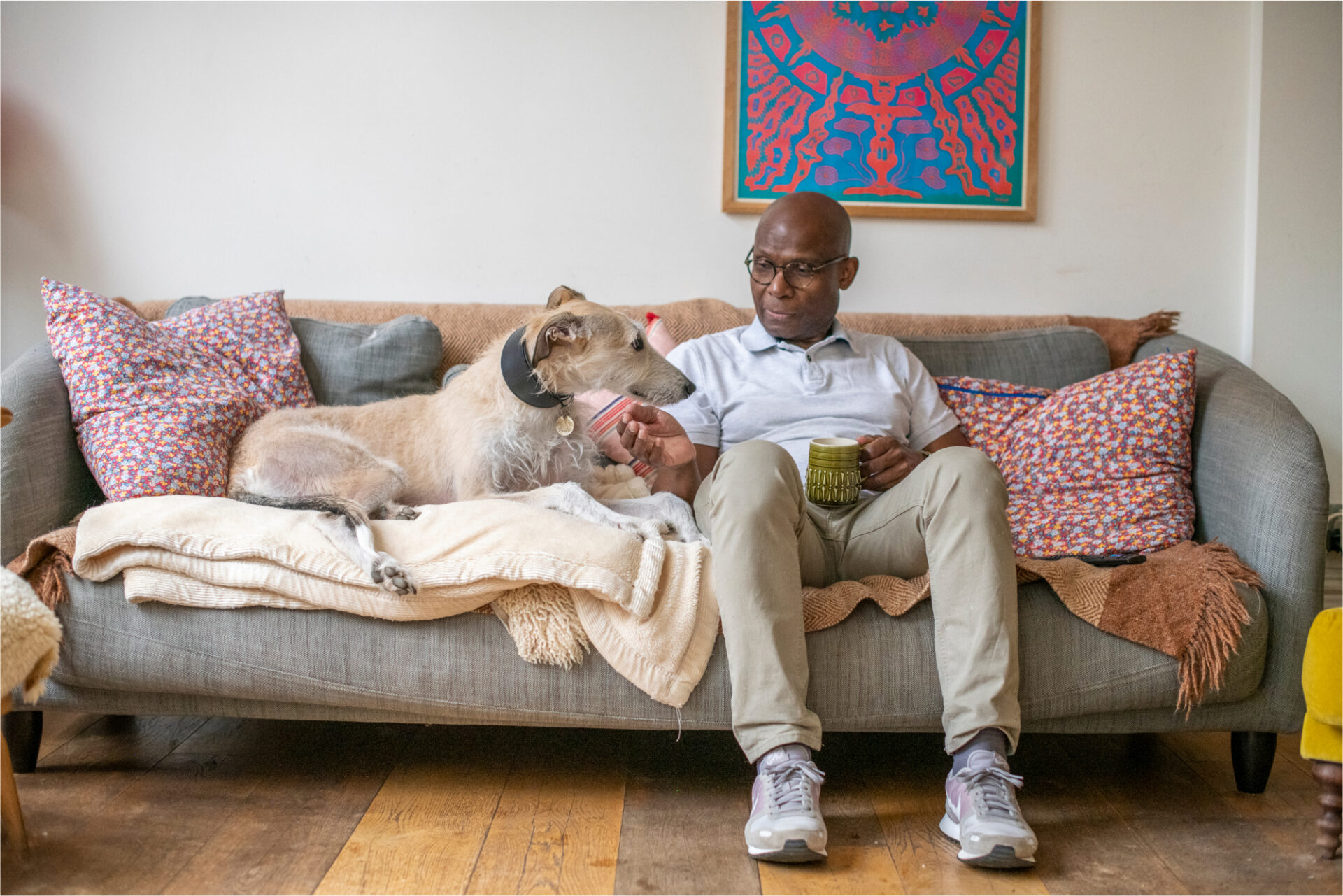 A dog and his owner seating on a sofa and looking at each other.