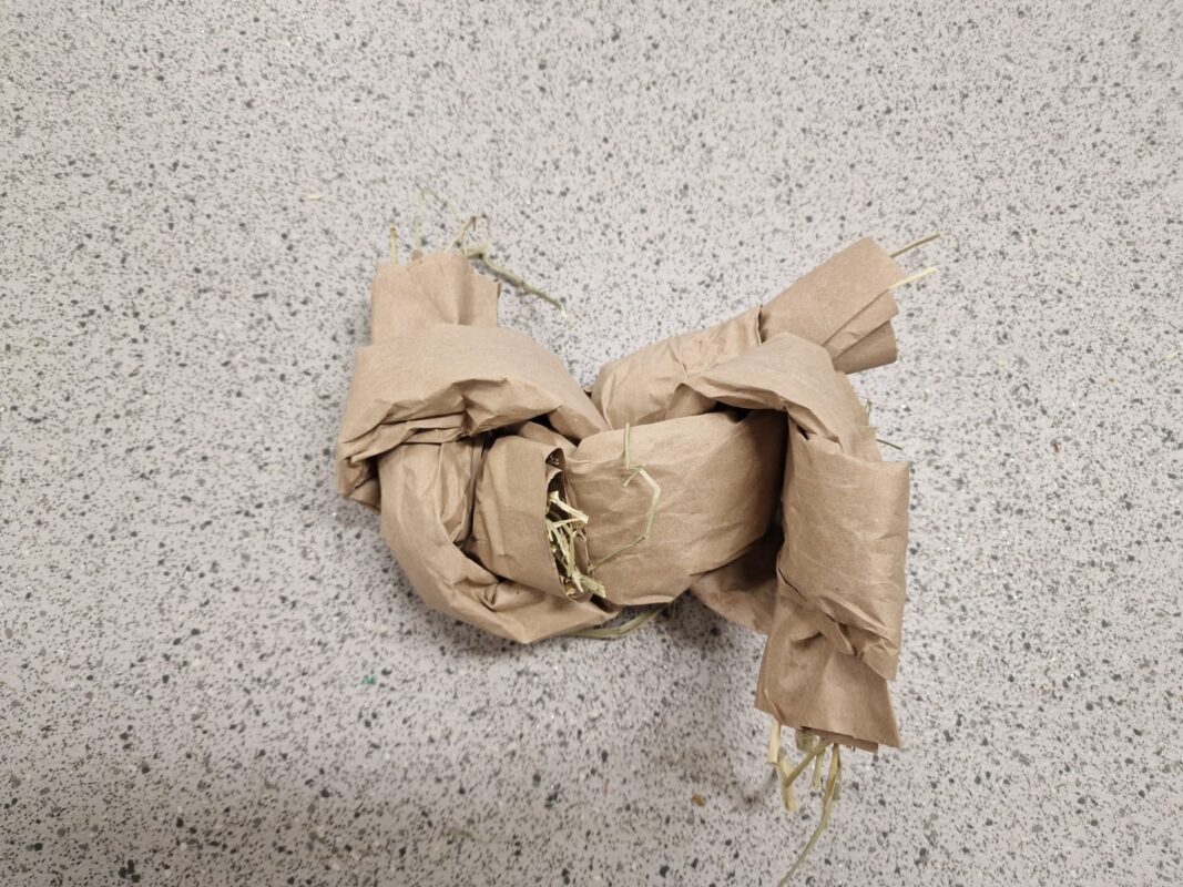 A hay toy for rodents made from brown paper.