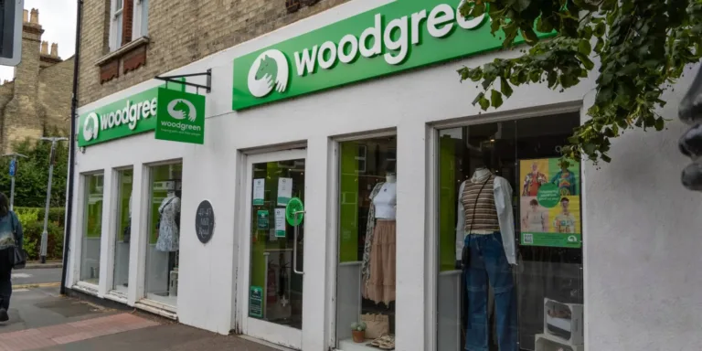 A storefront with a green and white woodgreen sign above the windows in Cambridge. Clothing and mannequins are displayed in the window, and a green hanging sign is visible near the entrance.